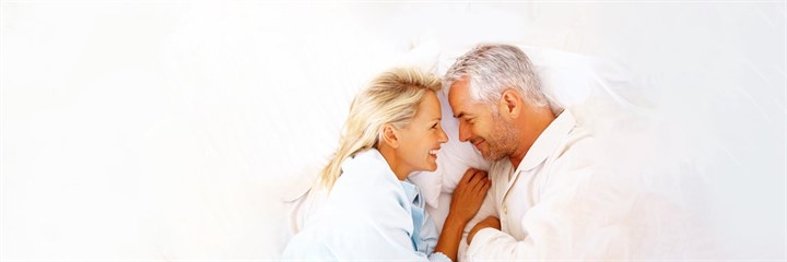 Middle-aged couple smiling in bed