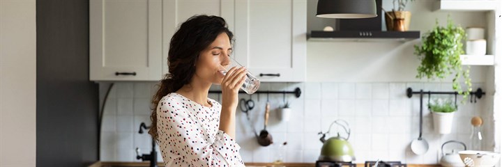 Woman drinking from a glass in a kitchen